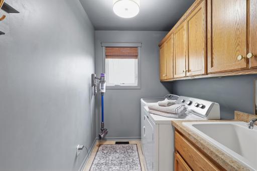 Main floor laundry room with cabinet storage and utility sink.