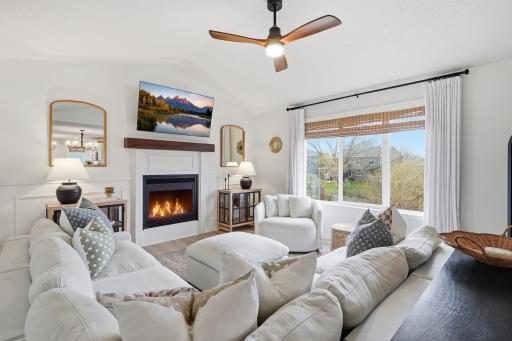 Bright living room with vaulted ceilings, large windows, gas fireplace, and updated finishes.