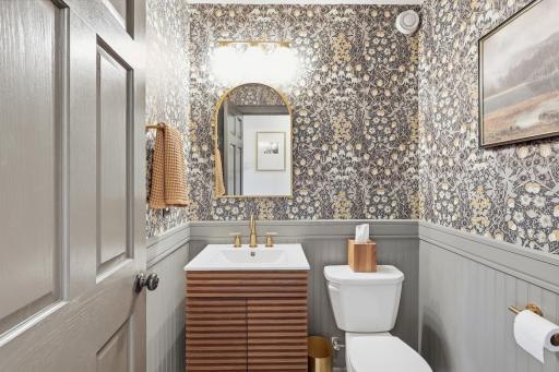 Fun powder room bath with board and batten, wallpaper, updated vanity, and light fixtures.