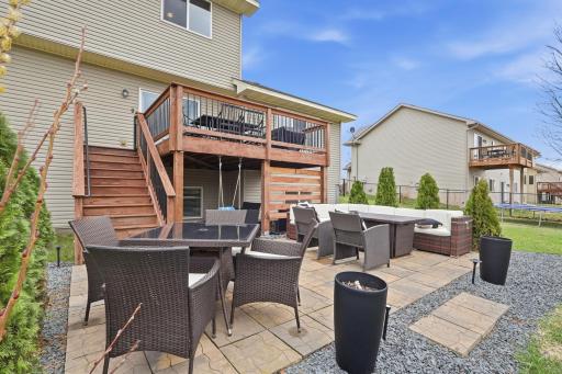 Fully fenced backyard with deck and stairs leading to spacious patio offering multiple areas for outdoor entertaining.