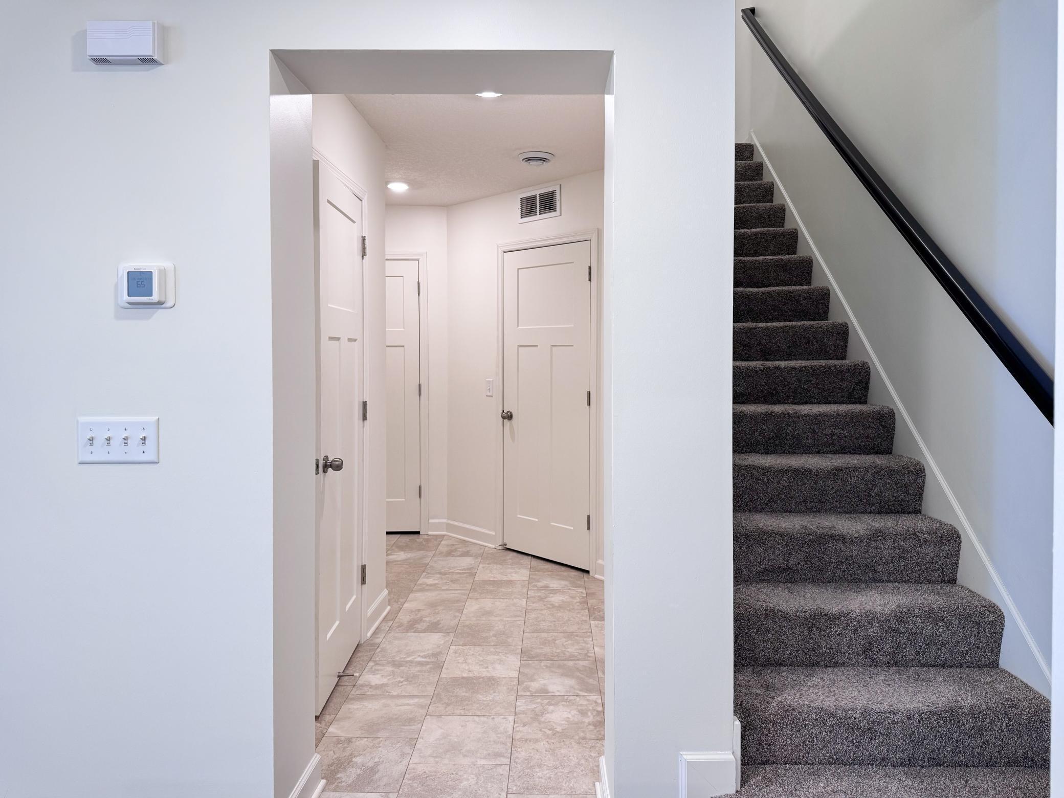 Hallway connecting to the garage and half bath and stairs to upper level