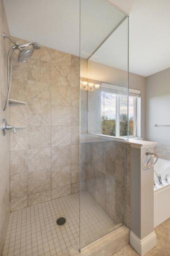 A large walk-in shower with custom tile, a soaking tub, and generous cabinet storage round out a bathroom that is equal parts practical and luxurious.