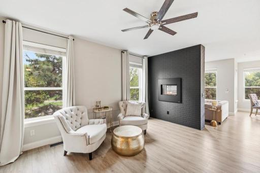 Sun-drenched and stunning â the living room features wide plank luxury vinyl flooring, oversized windows, and a double-sided gas fireplace with a dramatic black brick facade.