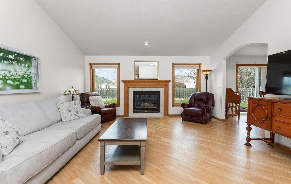 Living Room offers wood floors, vaulted ceilings, fireplace & views to fenced backyard.