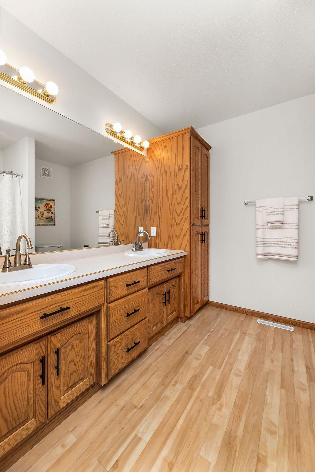 Primary Bathroom with double sinks, linen cabinet, & walk-in shower.