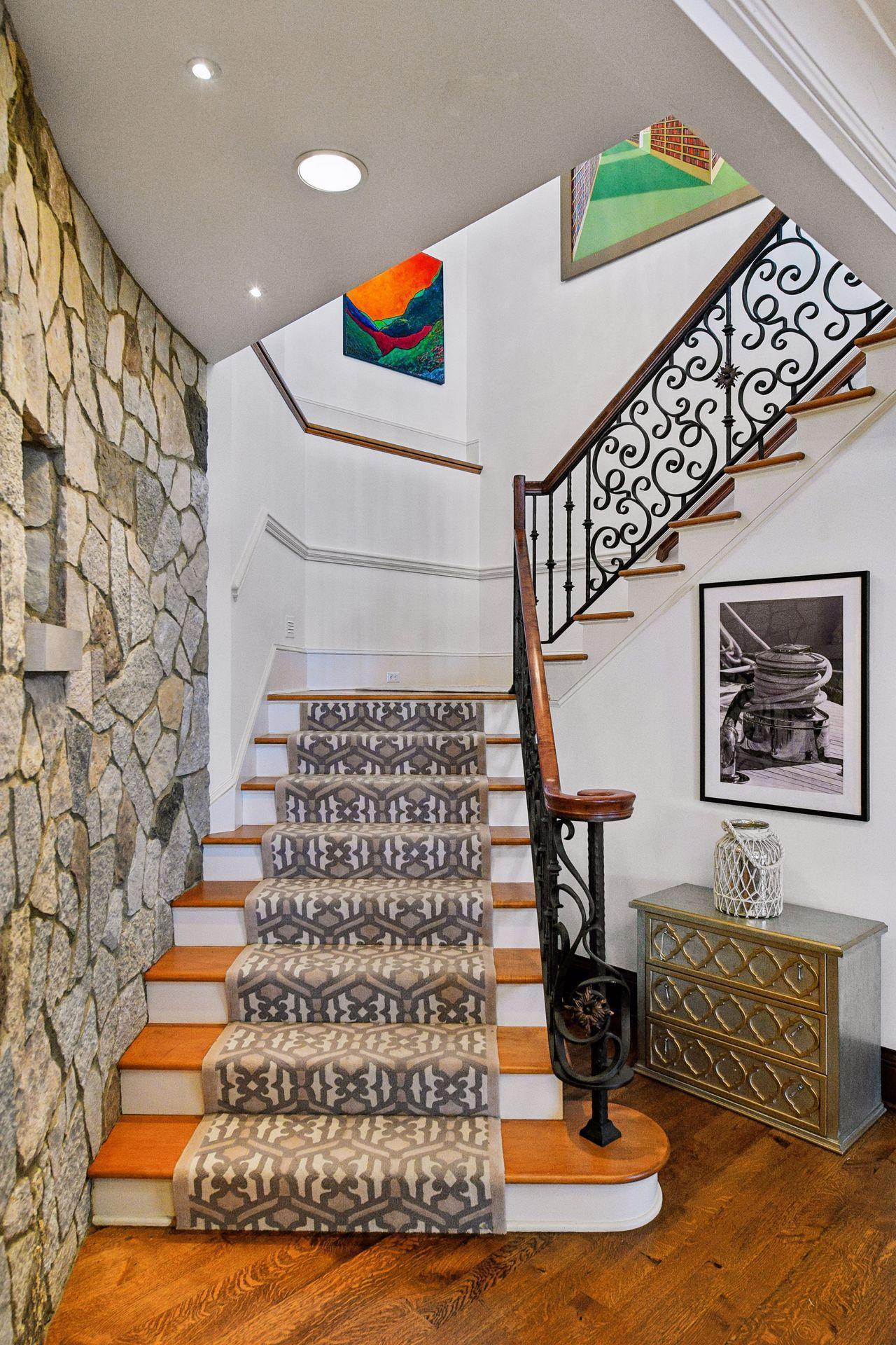 Glamorous and Ornate wrought iron and wood staircase leads down to an amazing lower level.