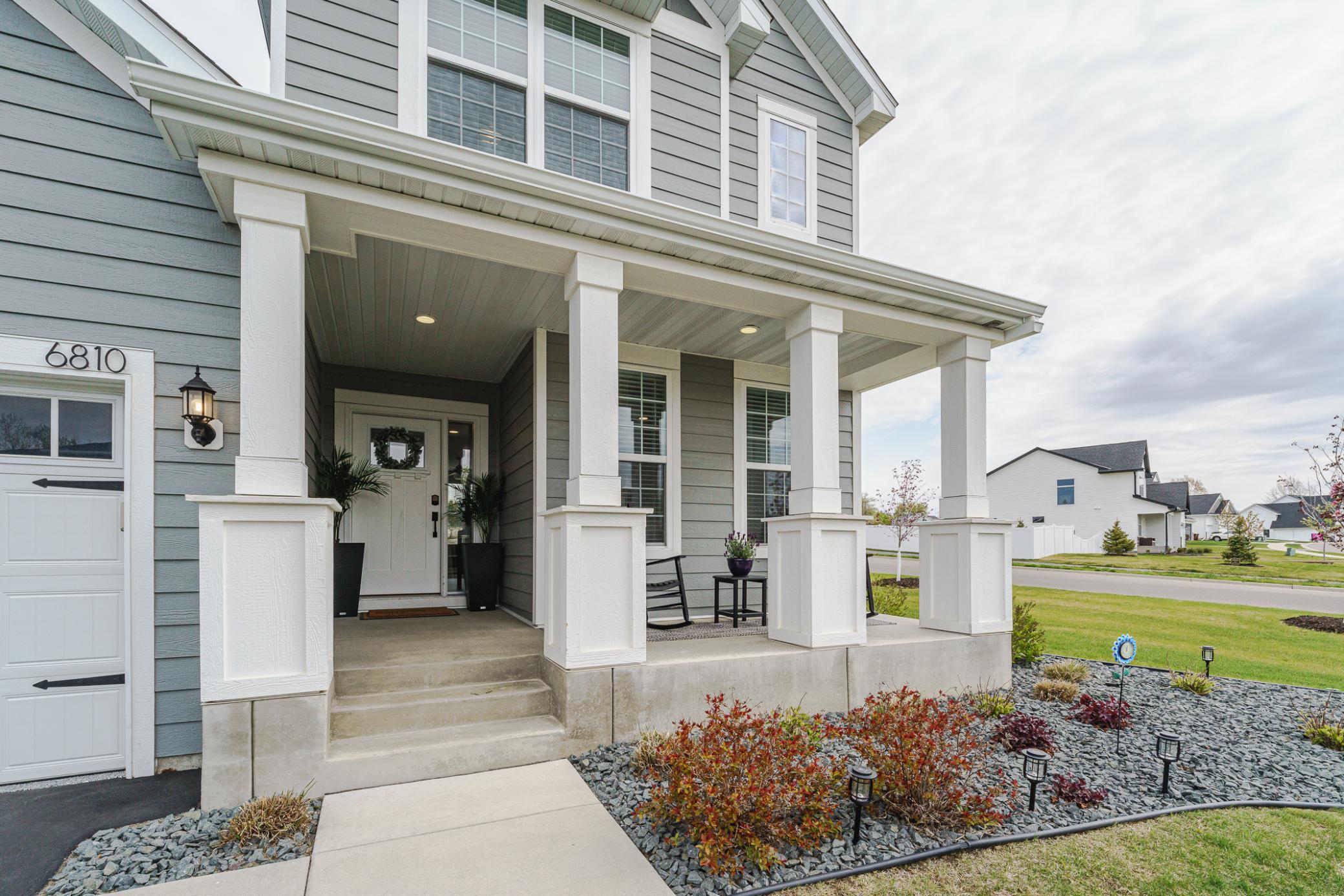 The covered front porch with pillars offers comfortable afternoon shade and a restful spot to watch what is happening in the yard.