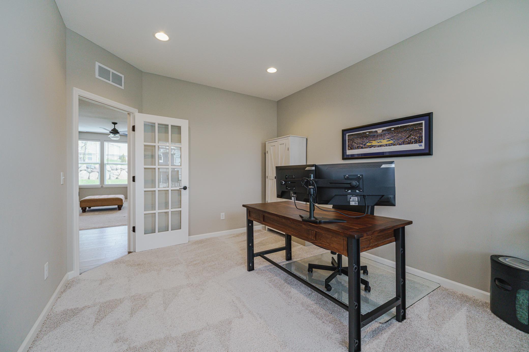 The office has a gridded glass door to the main living spaces.