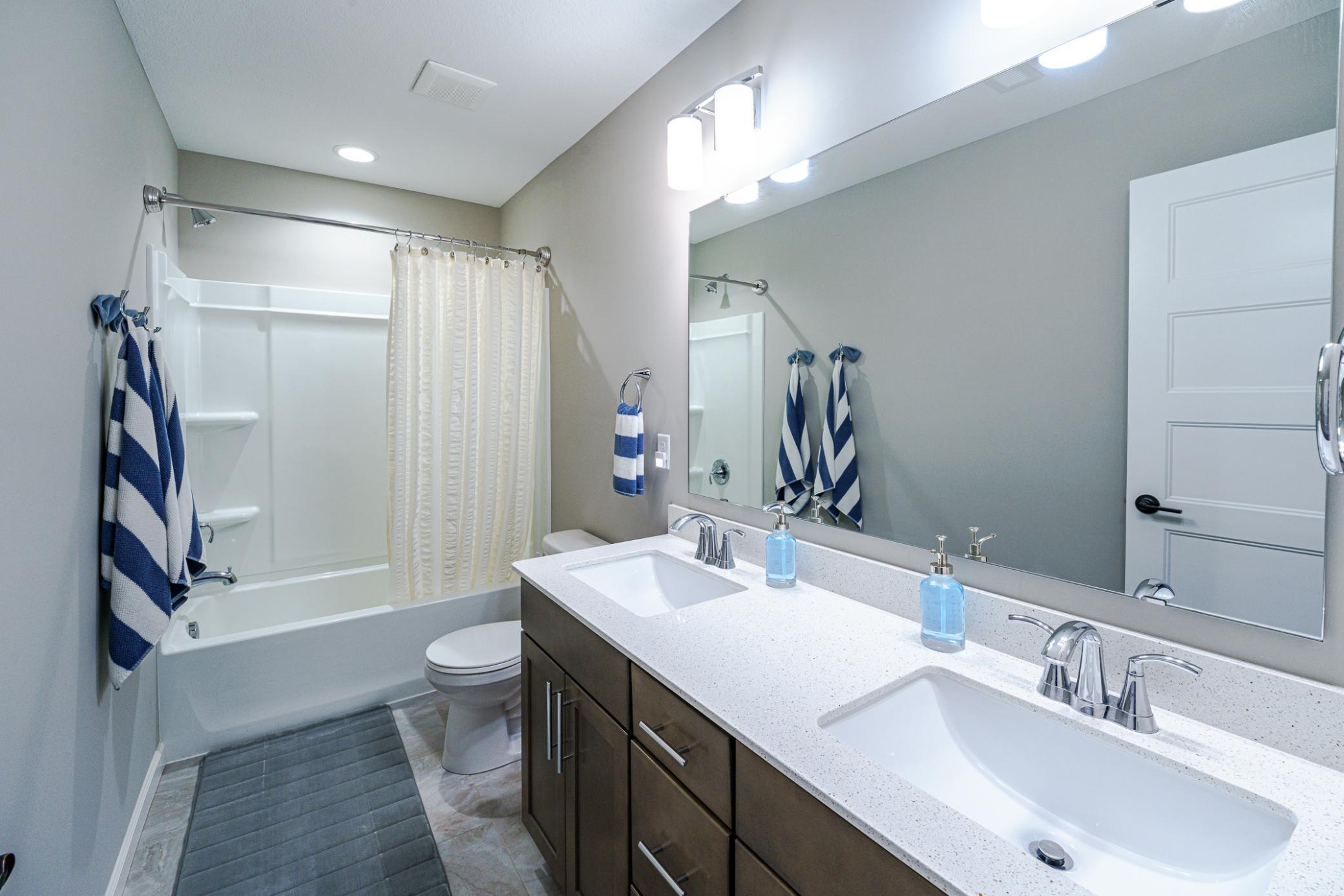 The full upper level bathroom has dual sinks and quartz surfaces. Linen storage lies in the hall.