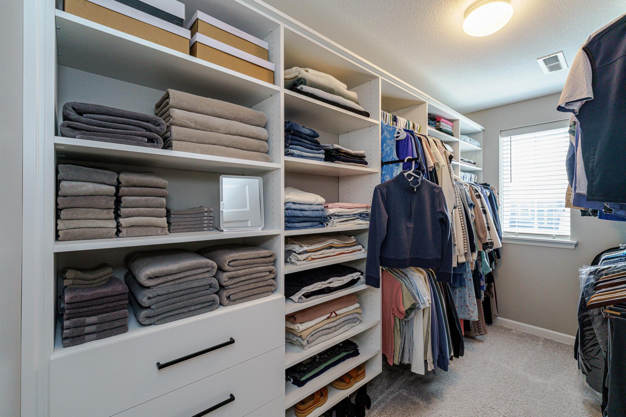 The walk-in closet features NEW CUSTOM CLOSET ORAGANIZERS with hanging rods and hangers for belts, as well as a window for natural light and ventilation.
