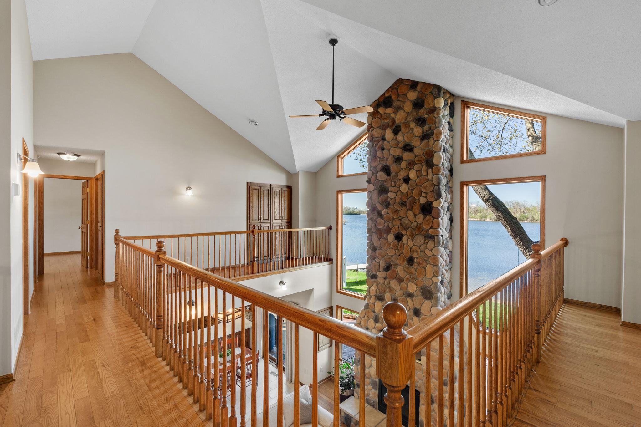 Vaulted ceilings and views of the stone fireplace and windows create an impressive upper-level hallway.