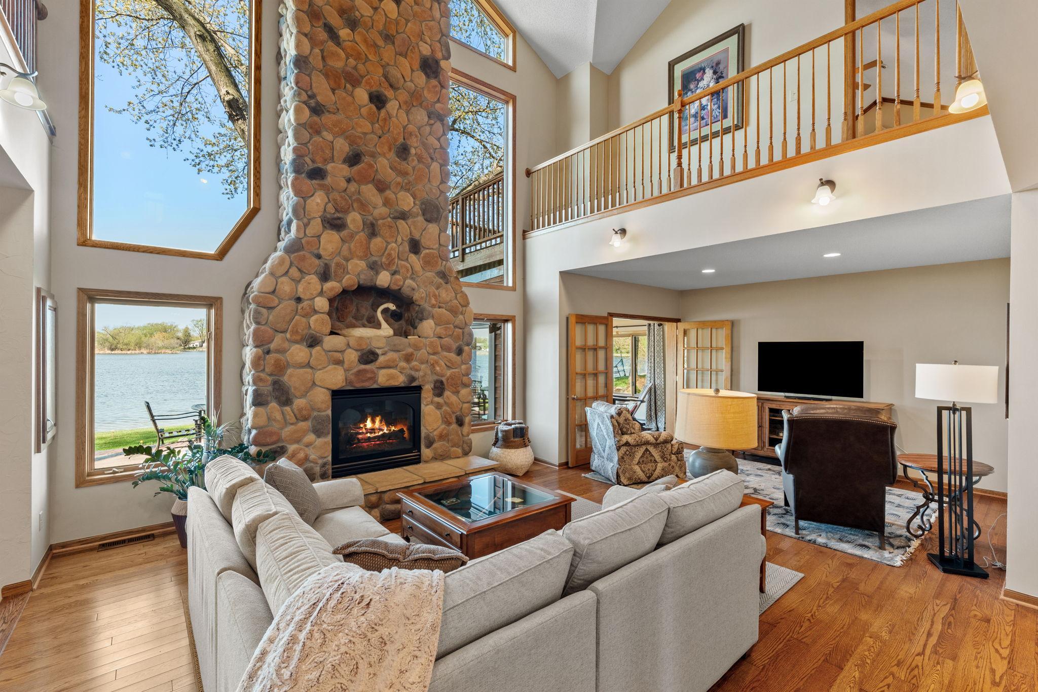 Natural light pours into the great room through a dramatic wall of windows, showcasing breathtaking lake views.