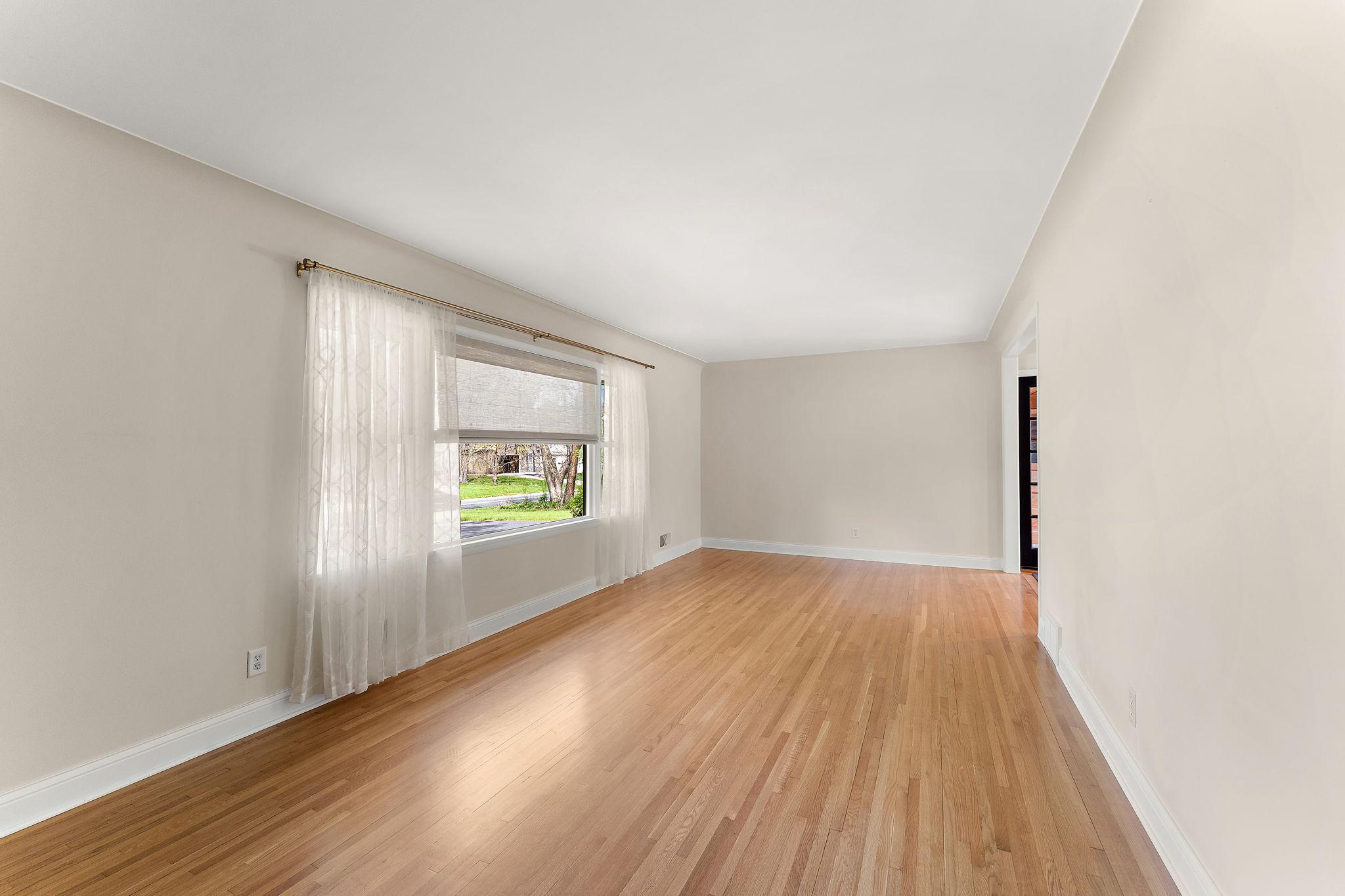 Looking into the Living Room from the foyer. This is part of the original home, but has a new custom window, fresh paint & gleaming oak flooring.