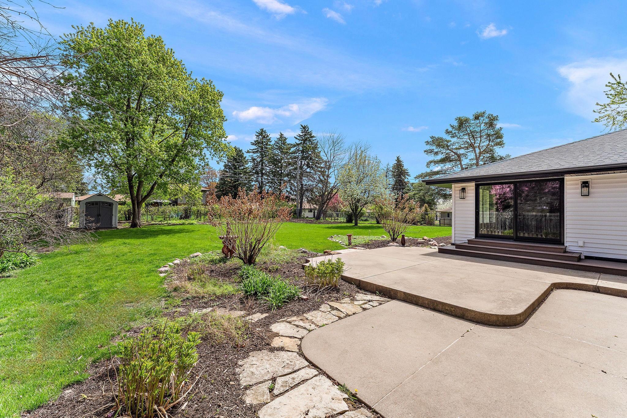 The concrete patio features stone edging & walkways. There are areas for it all- a dining table & lounge chairs.