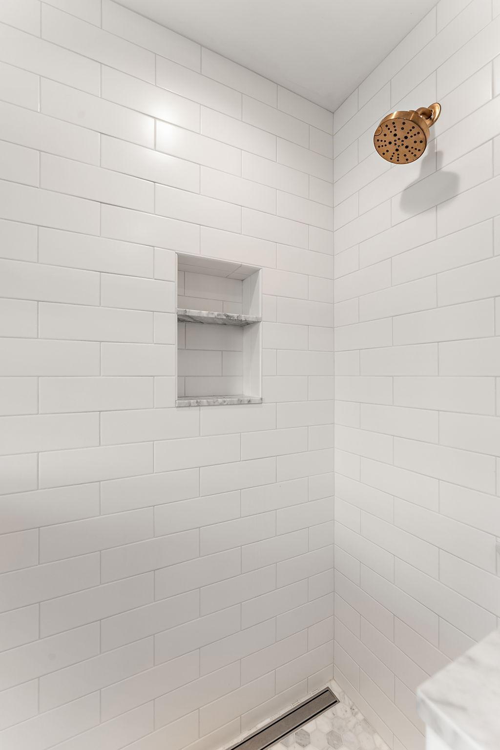 Subway tile walls, marble floors & niche.
