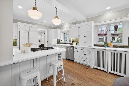 The spacious eat-in kitchen showcases custom cabinetry and original French doors that open seamlessly to the backyard.