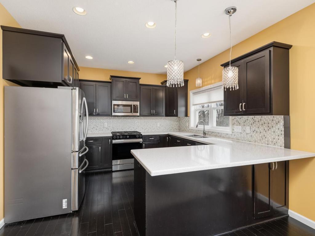 Well-appointed & functionally designed Kitchen features stainless steel appliances, quartz countertops, and breakfast bar seating.