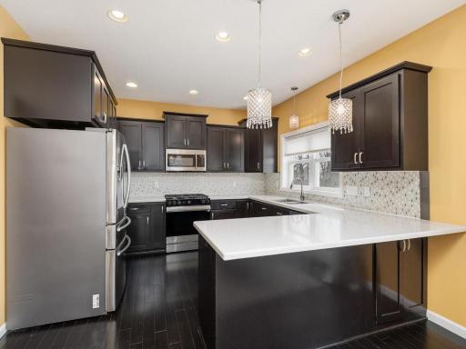 Well-appointed & functionally designed Kitchen features stainless steel appliances, quartz countertops, and breakfast bar seating.