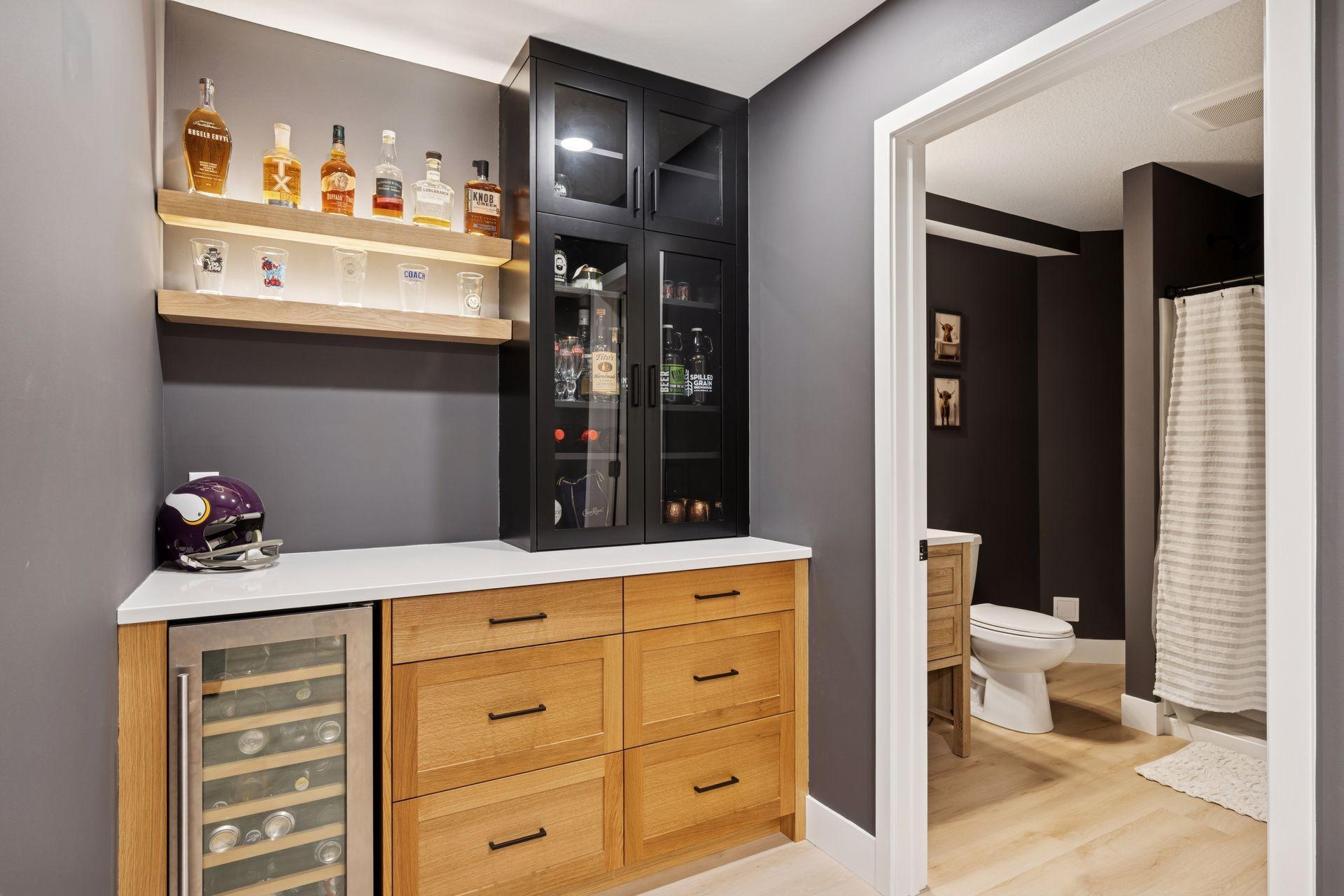 Custom finished base with white oak base cabinets, quartz countertop, black tower with glass doors, and rift white oak backlit floating shelfs.