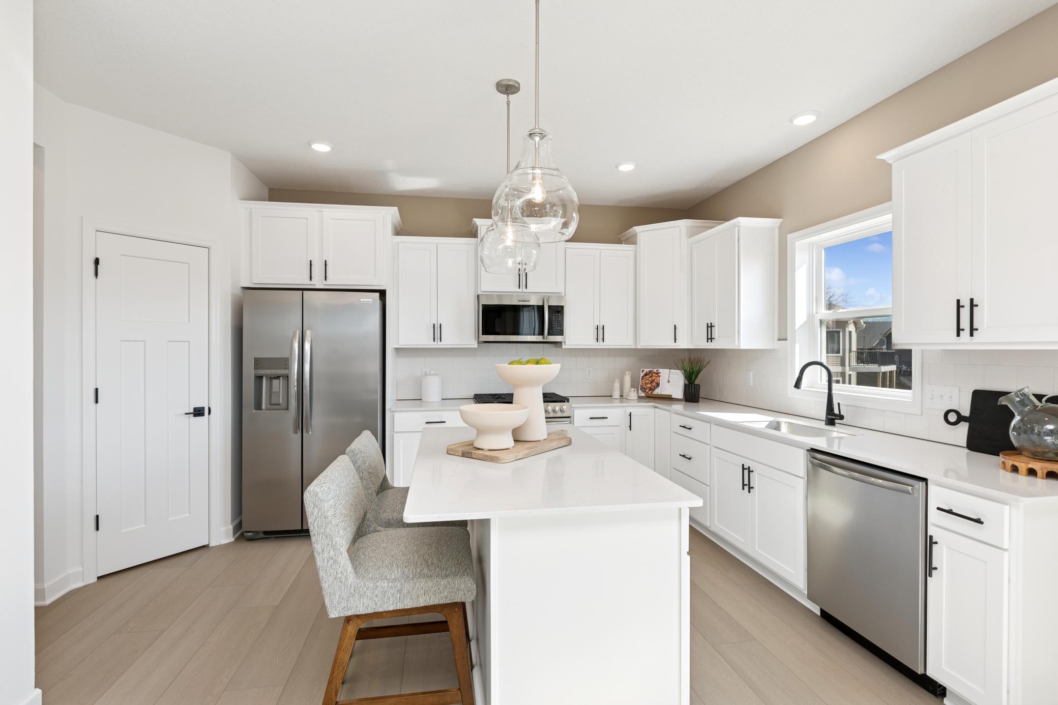 (Photo of Actual Model Home) The spacious kitchen features brand-new stainless steel appliances, a center island and ample cabinetry storage.