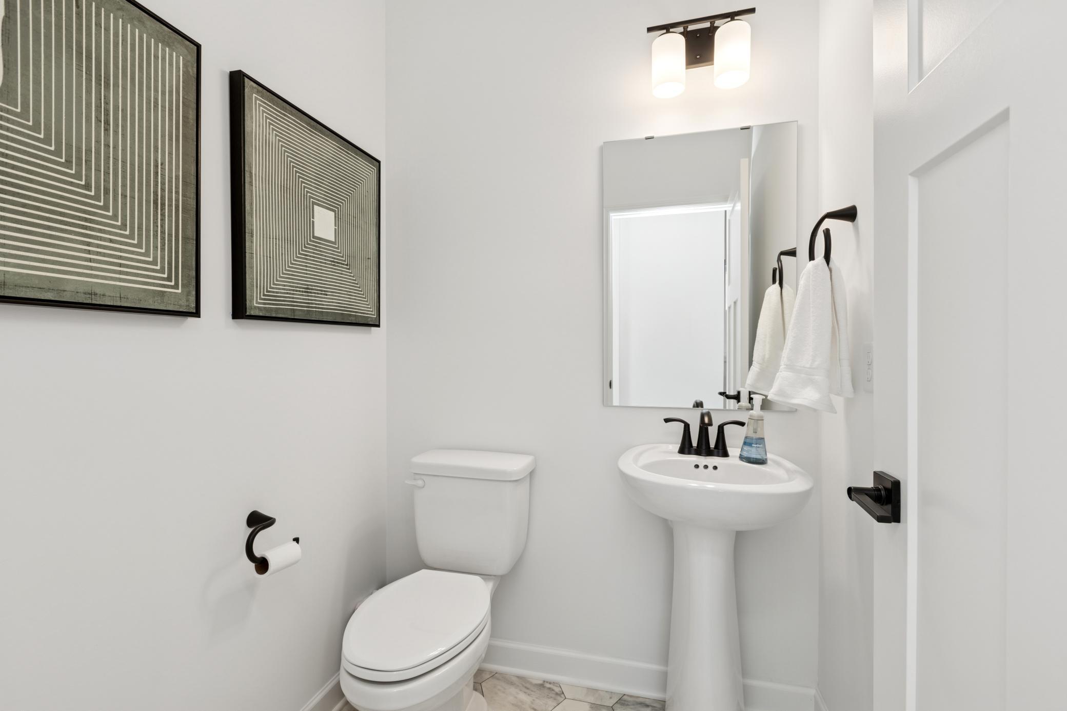 (Photo of Actual Model Home) The powder room is easily accessible from the communal living spaces.