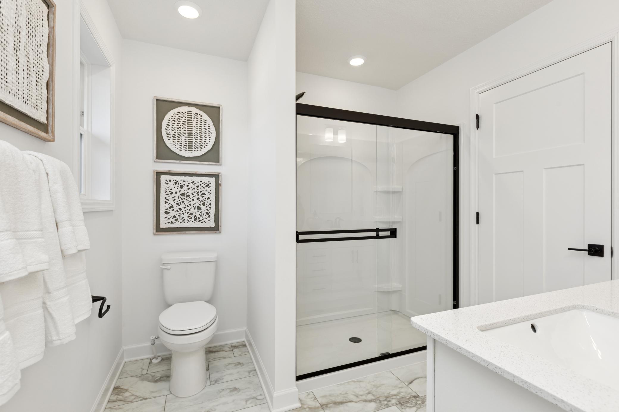 (Photo of Actual Model Home) Along with a sophisticated glass-enclosed shower, the en-suite bathroom features convenient access to the walk-in closet
