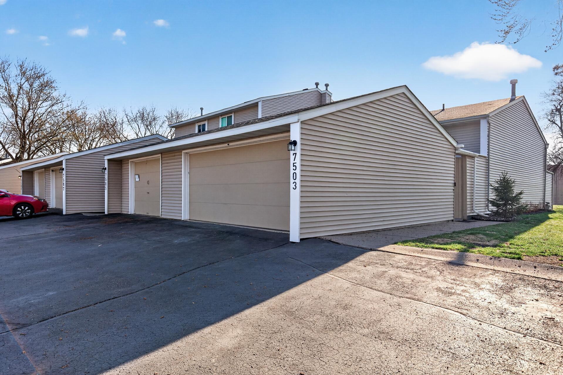 End-unit exterior featuring an oversized detached two-car garage, additional driveway parking, and convenient guest access.