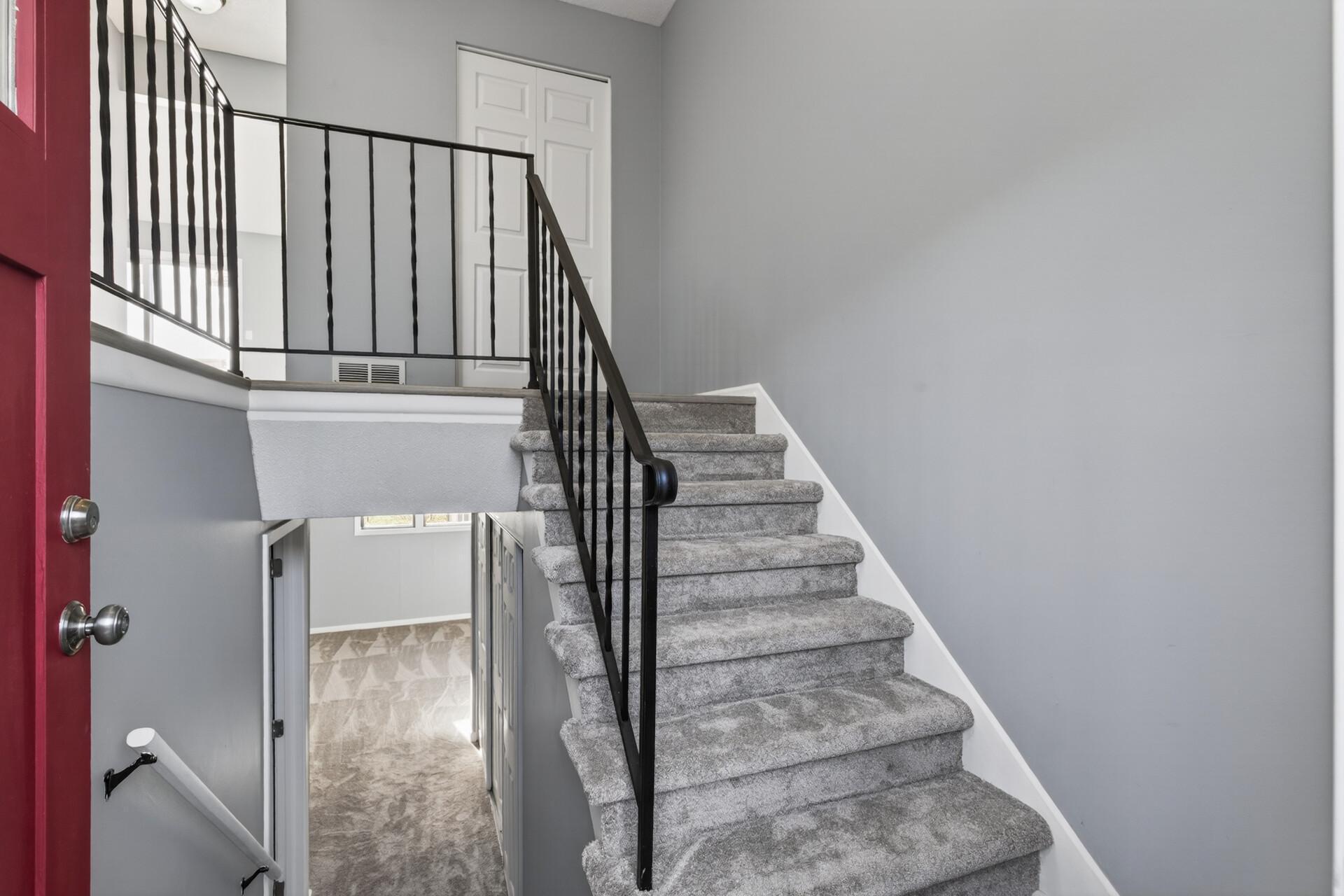 Split-entry foyer with fresh neutral paint, updated carpet, and modern black railing accents.