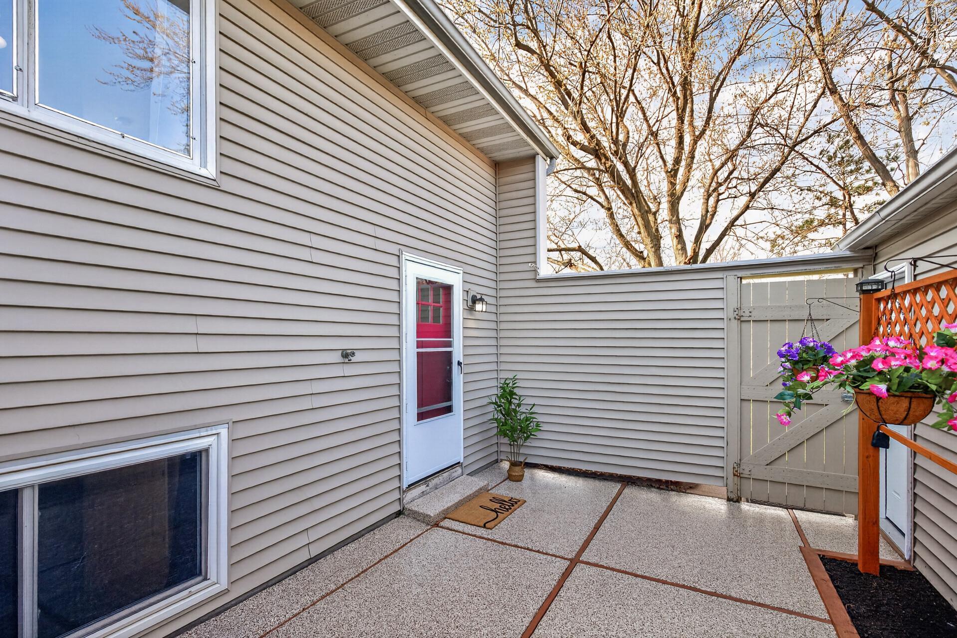 Private fenced courtyard entry with low-maintenance patio surface, charming gate, and welcoming front door.
