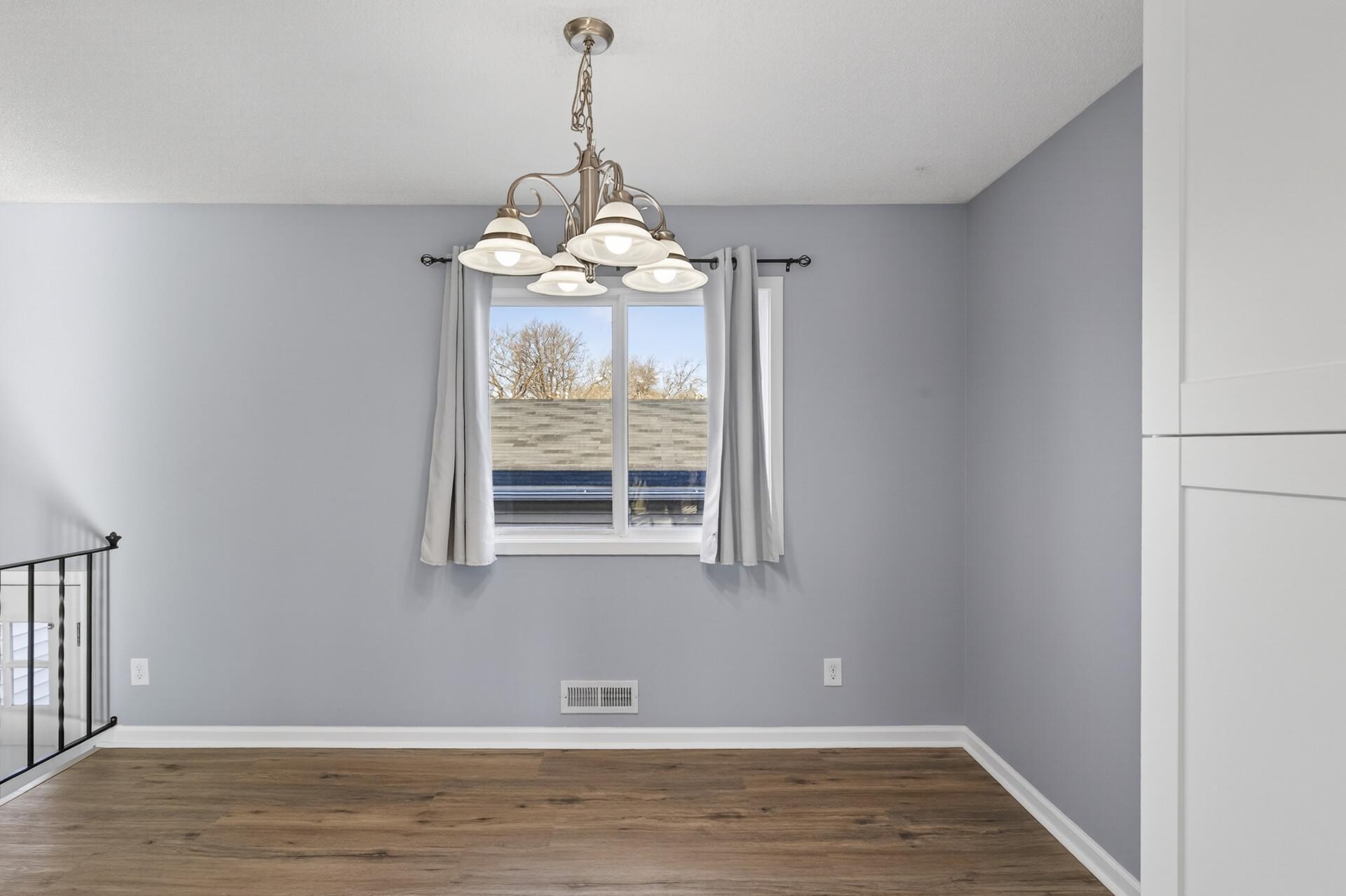 Bright dining area with updated flooring, neutral paint, and large window for natural light.