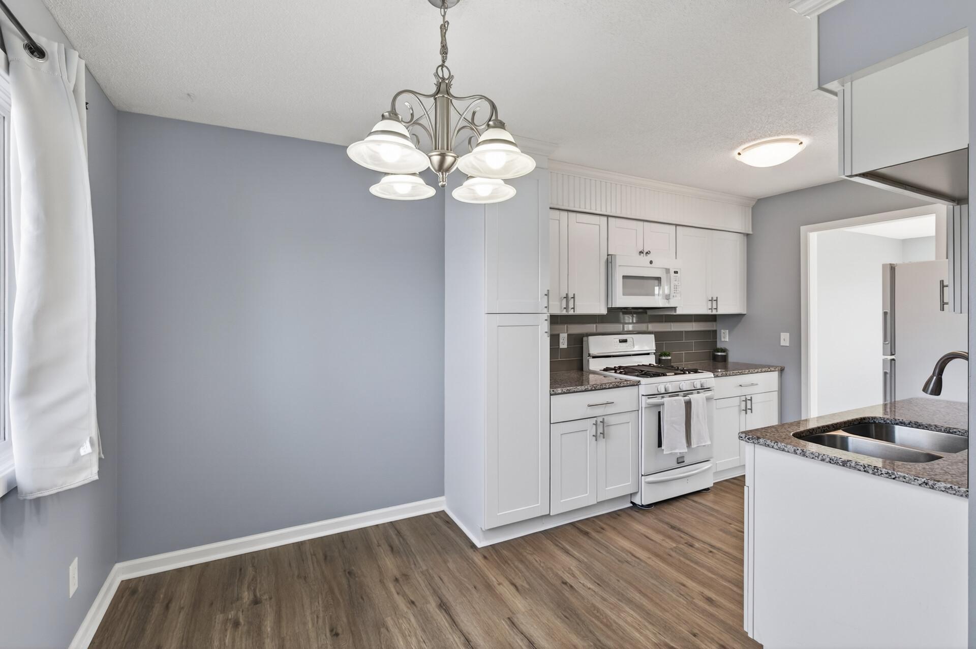 Remodeled kitchen with white cabinetry, granite countertops, subway tile backsplash, gas range, and stainless sink.