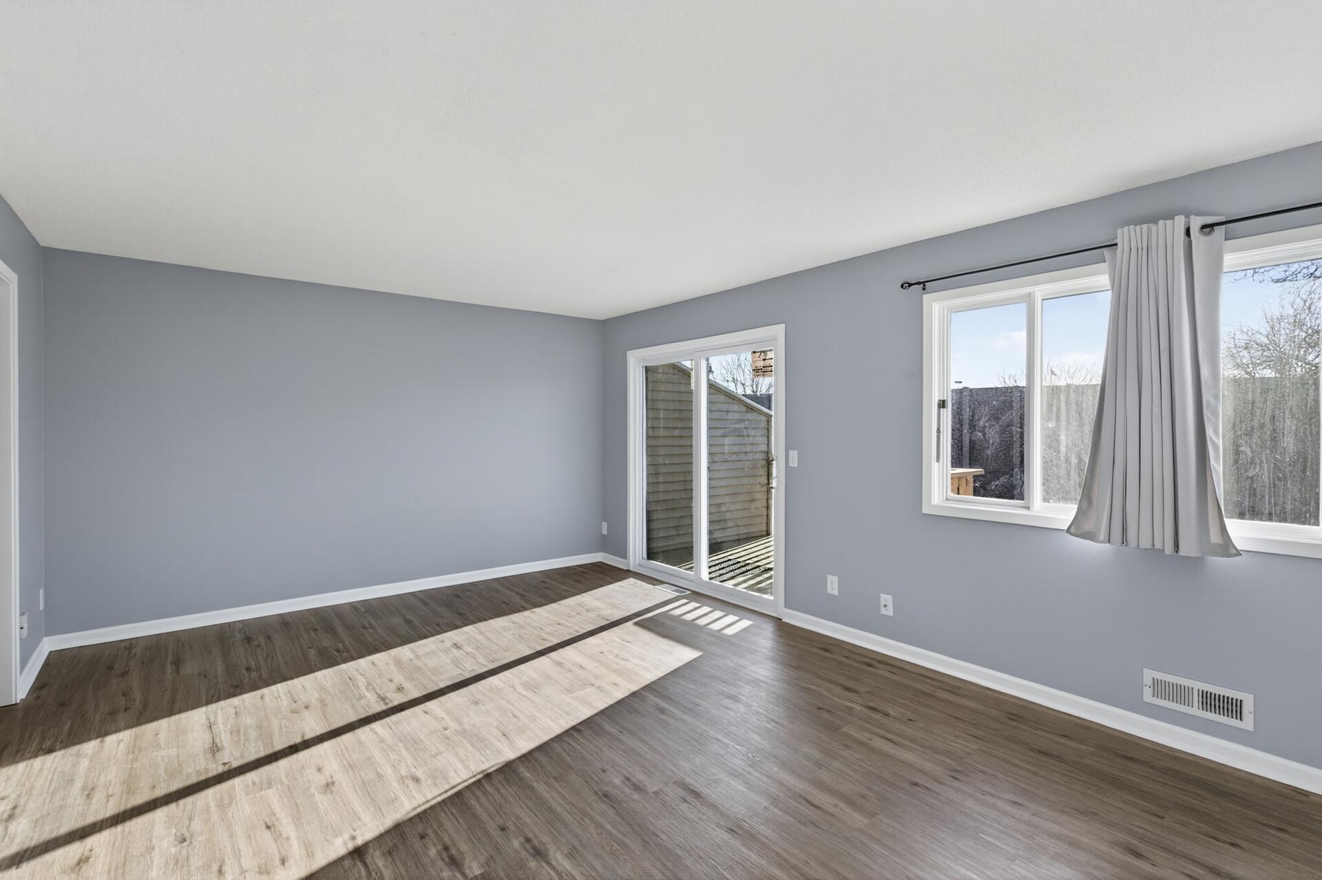 Another perspective of the upper-level living room highlighting expansive wall space and easy connection to the kitchen.