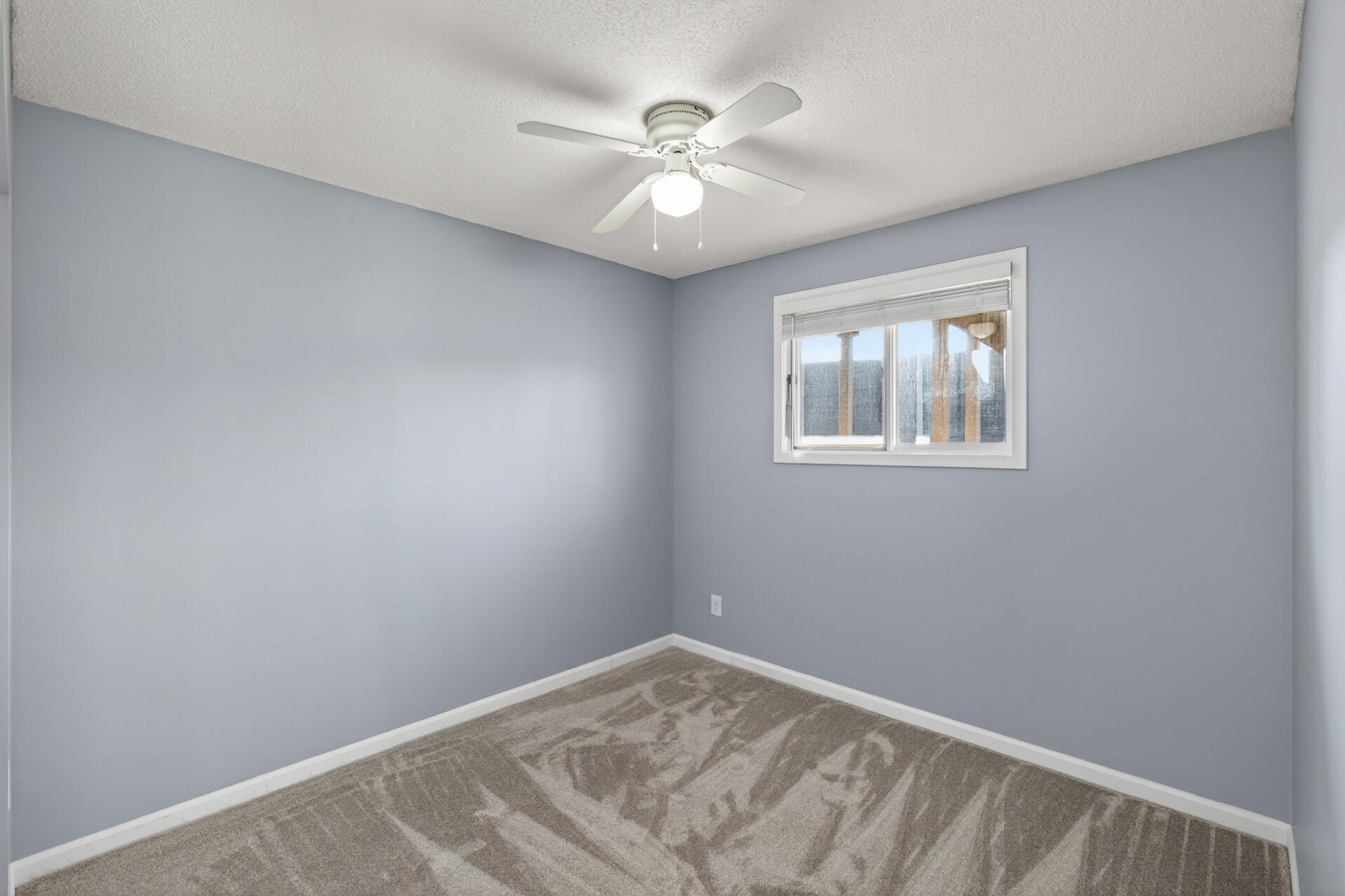Secondary lower-level bedroom with updated carpet, neutral tones, and a clean, move-in ready feel.