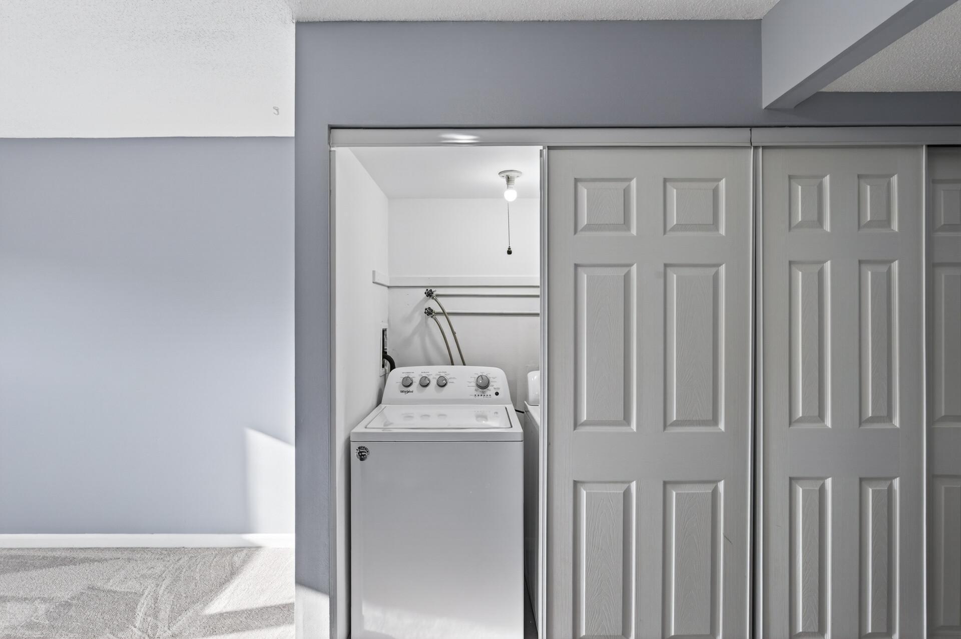 Convenient in-unit laundry area with additional storage space tucked neatly behind sliding doors.