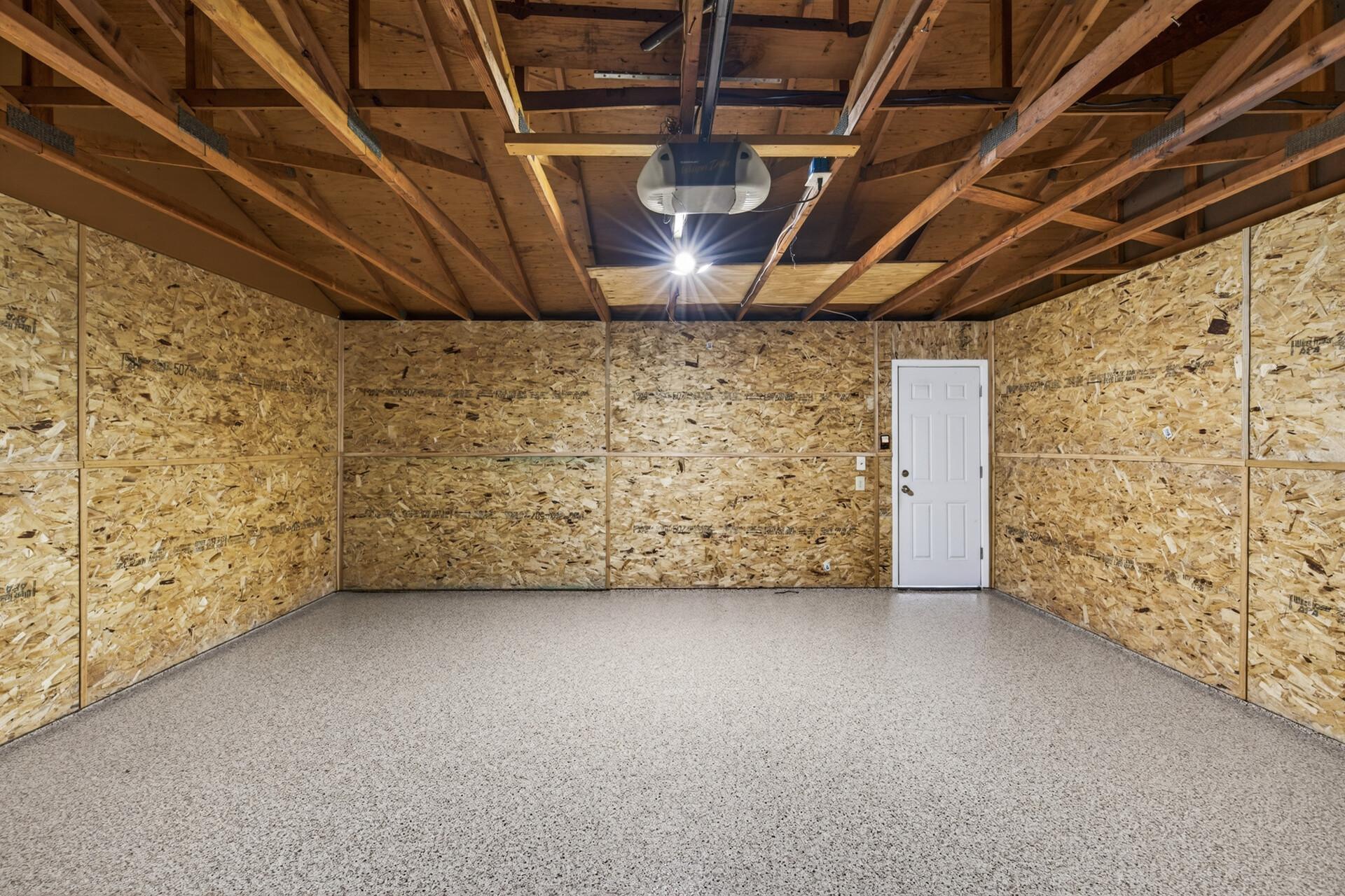 Interior view of the spacious garage highlighting clean finishes, overhead door, and versatile storage/workshop options.