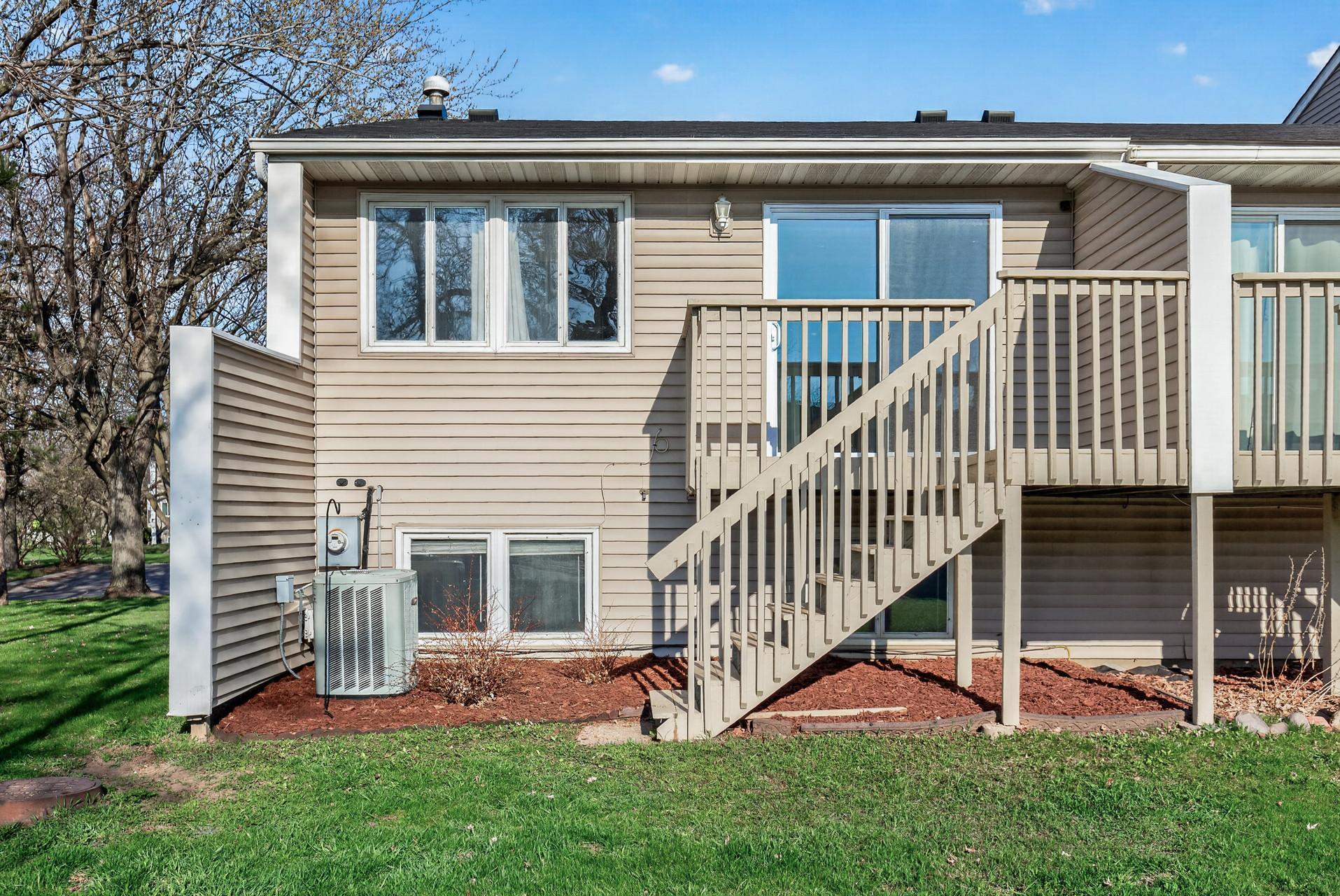 Rear exterior view showcasing deck access, lower-level windows, fresh landscaping, and outdoor space.
