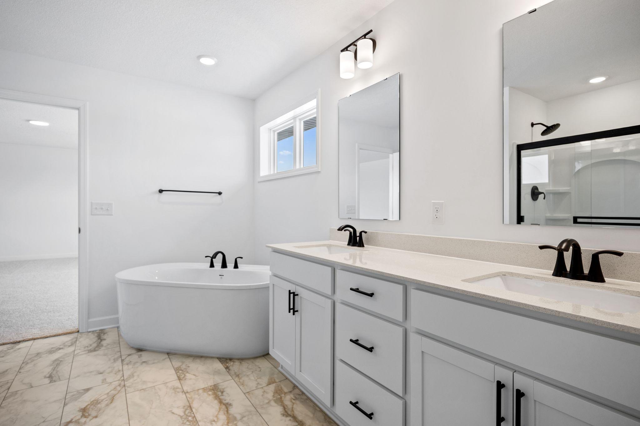 (Photo of a similar home, actual finishes may vary) A freestanding tub offers rejuvenating spa-like experiences while a glass-enclosed shower streamlines daily cleansing rituals