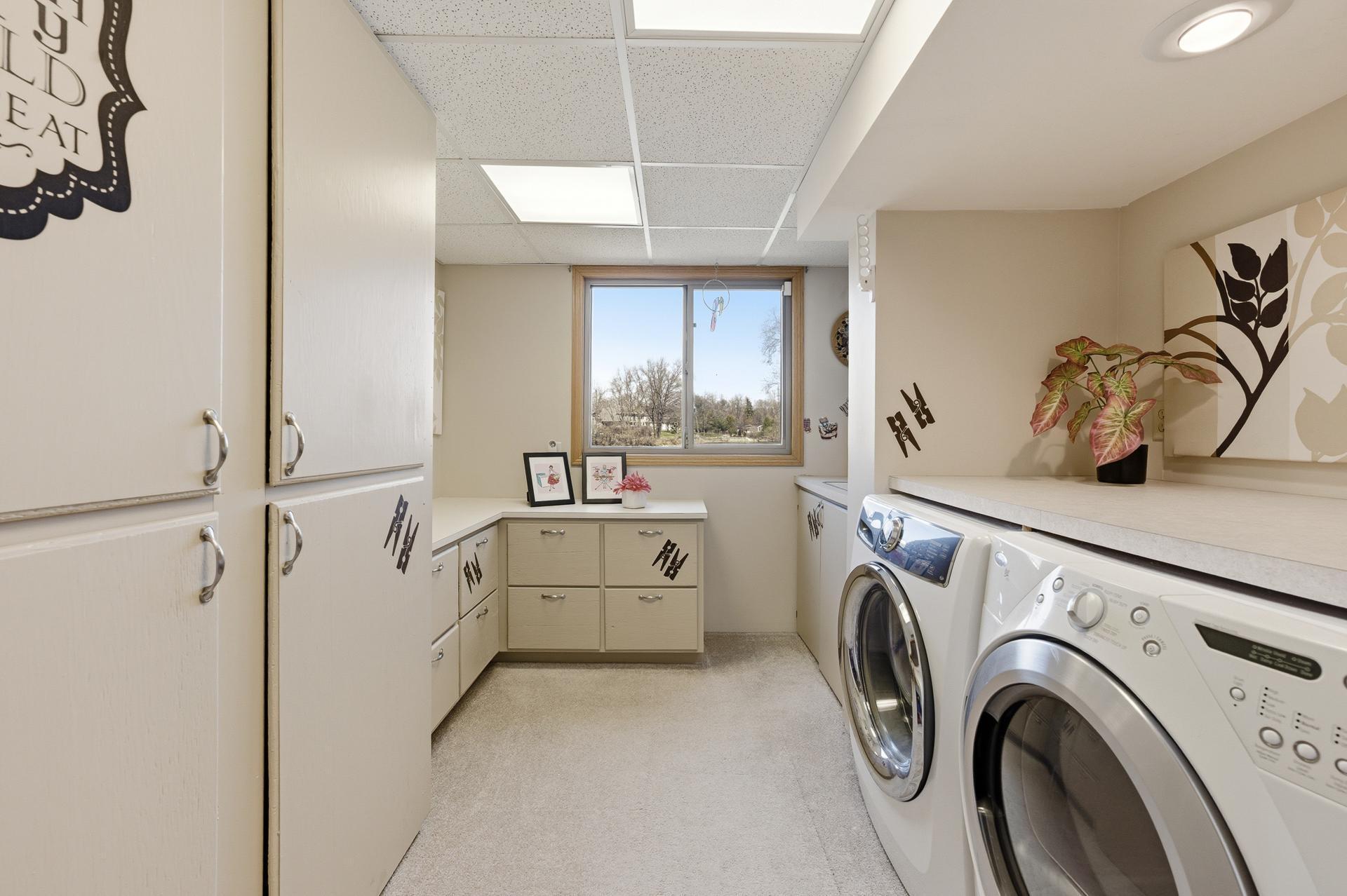 Lower level Laundry room with utility sink (to left of W/D) and storage cabinets.