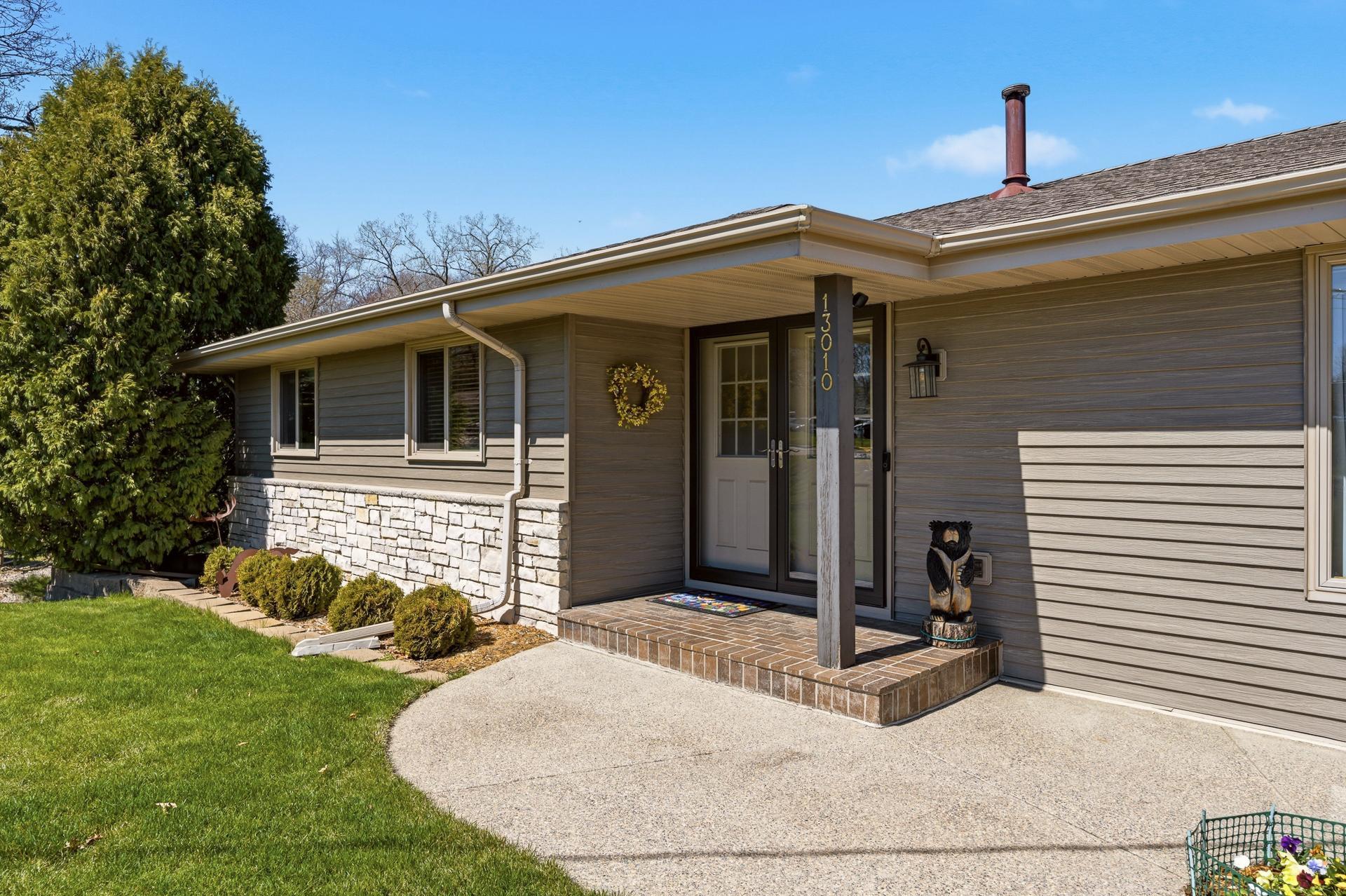 Wide aggregate sidewalk leading to the covered front entry. Rain gutters with screen filters.