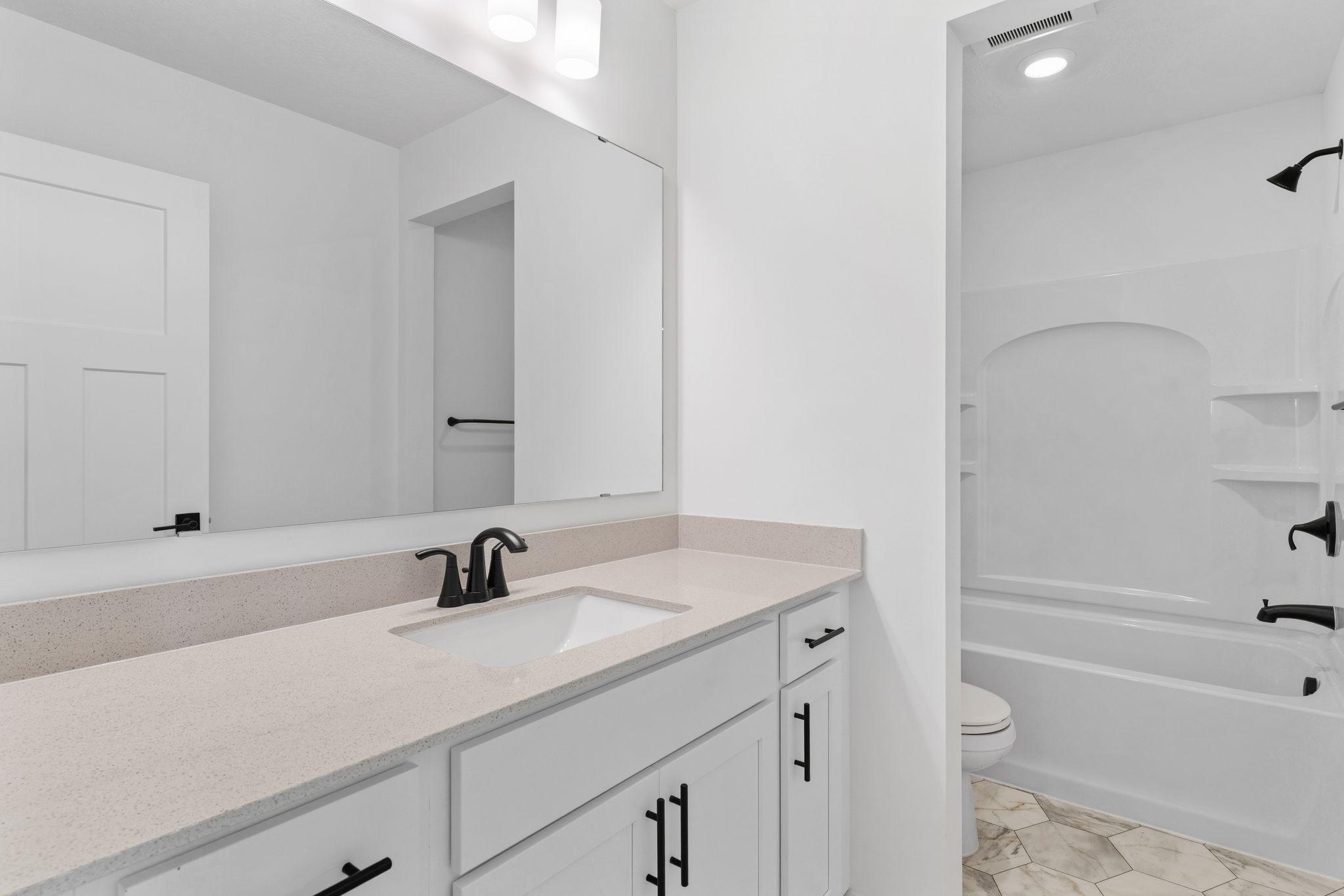 This full bathroom features a wide single vanity and shower-tub combination.