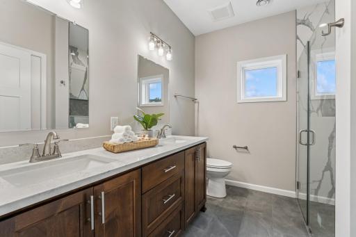 The owner's ensuite bathroom is beautiful with quartz and custom cabinets and walk-in shower and large linen closet