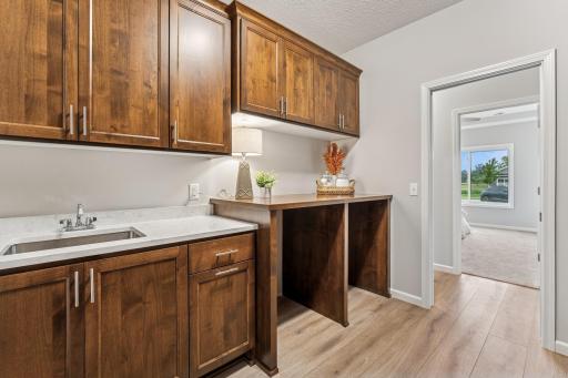 A surprisingly large laundry room with sink, Quartz countertops and wow custom cabinetry offering so much room for storage and organization.