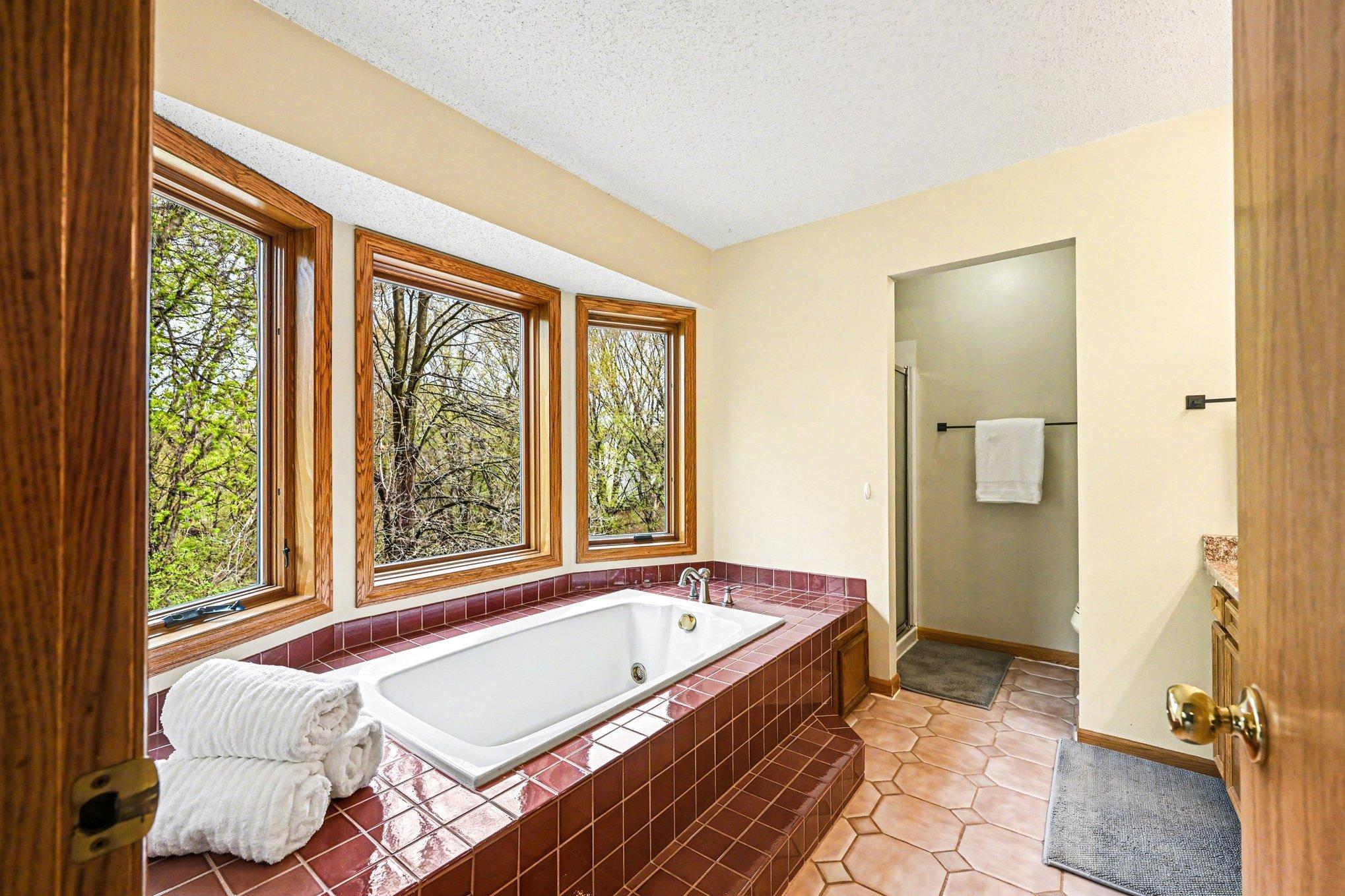 Spacious tub with windows overlooking the backyard provides a peaceful setting as you unwind from the day.