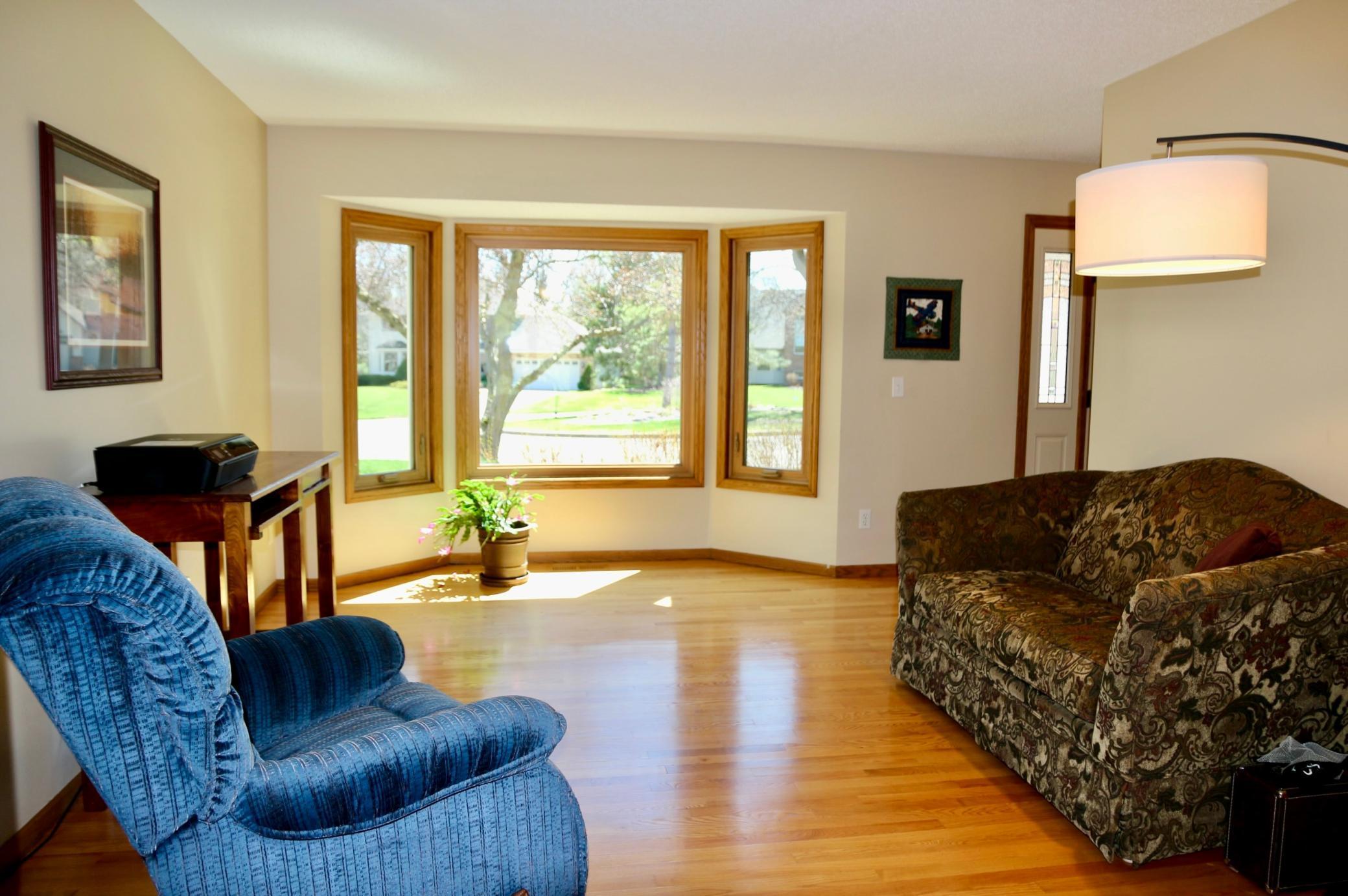 Bright living room featuring a front bay window that fills the space with natural light