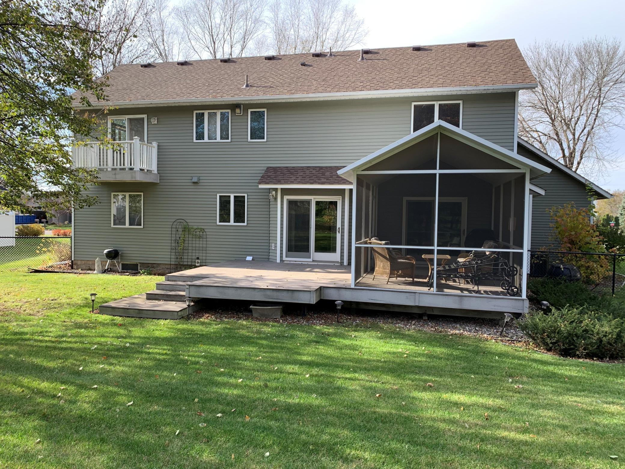 The rear of the house showing the deck off the primary bedroom, patio, and screened in porch. All maintenance free.