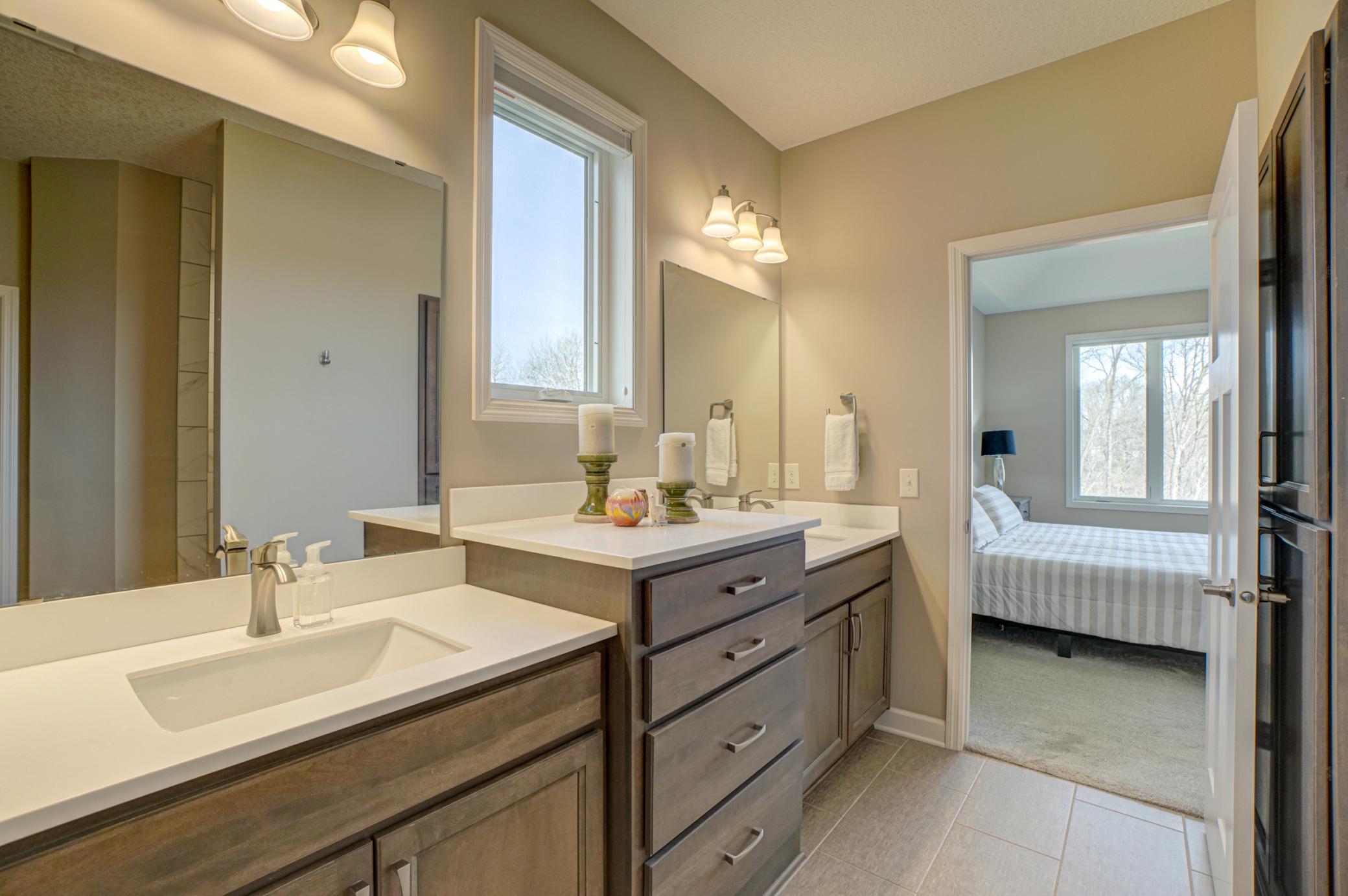 Enjoy spa-like comfort in this private primary bath with double sinks, a tiled shower, and spacious walk-in closet