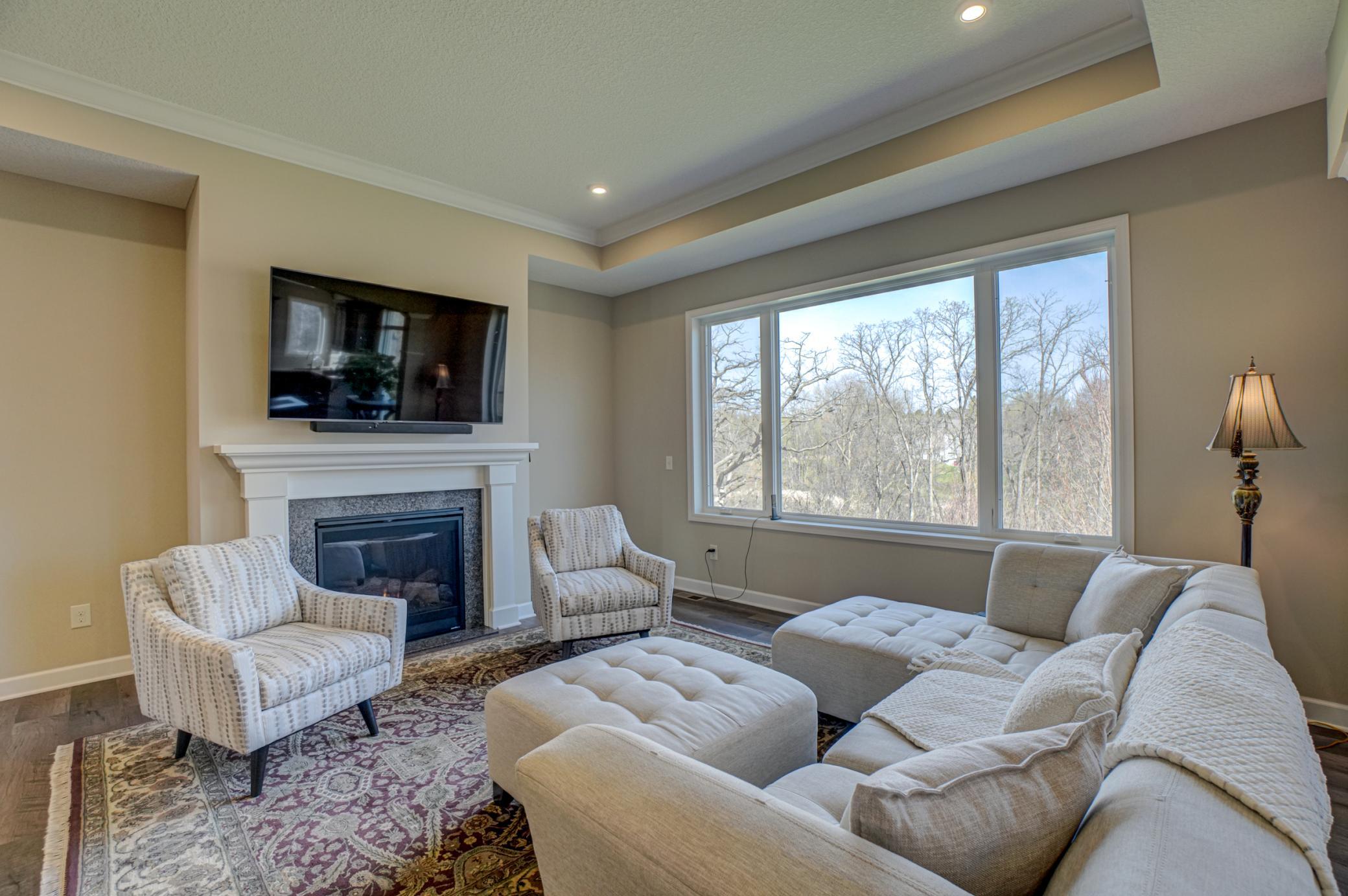 The spacious great room fills with natural light and perfectly frames the picturesque backyard, highlighted by a cozy gas fireplace—ideal for relaxing or entertaining