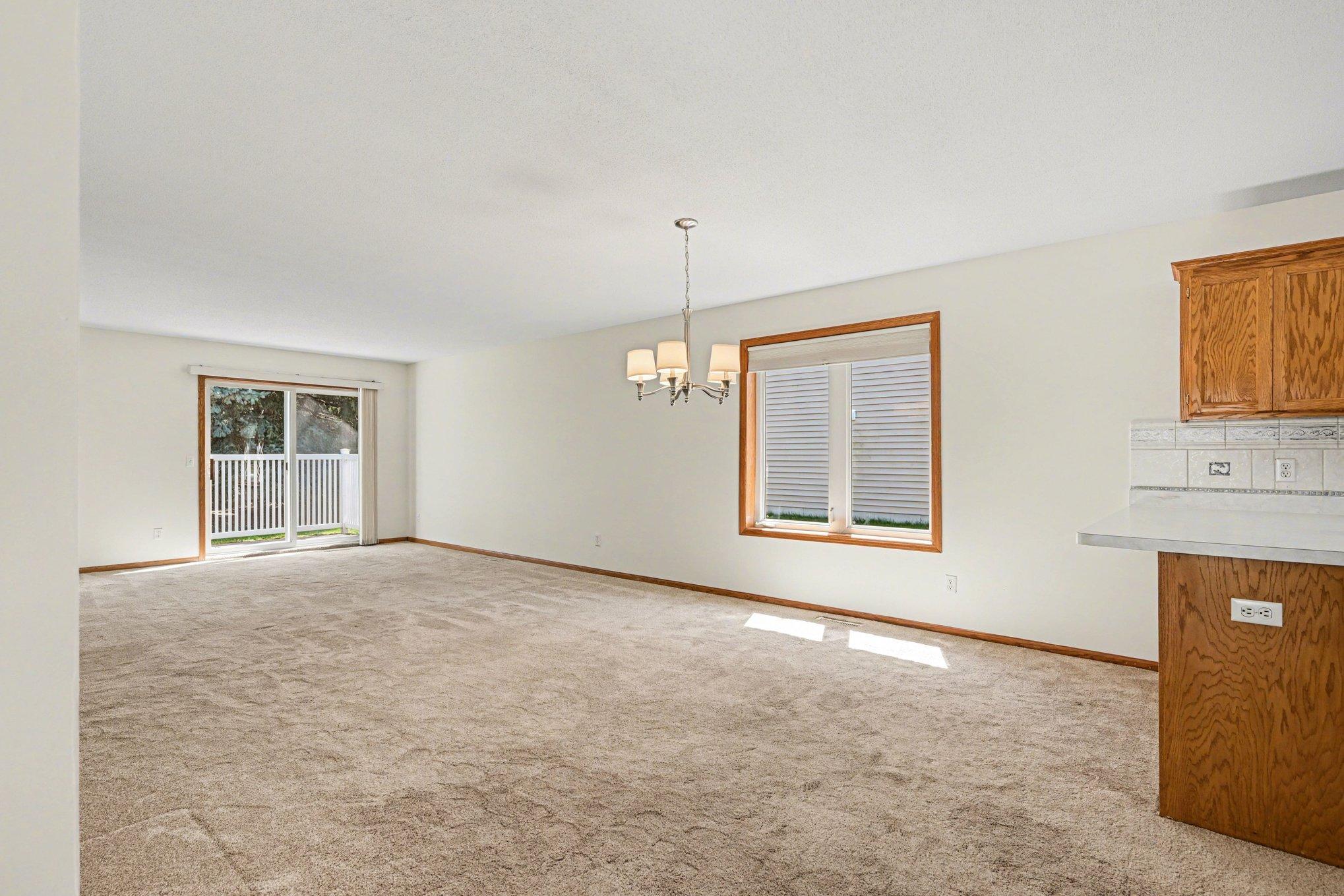 This view highlights the large window and patio door that flood the room with natural light. Freshly painted and move-in ready, this bright, open space seamlessly connects indoor comfort with your private outdoor retreat.