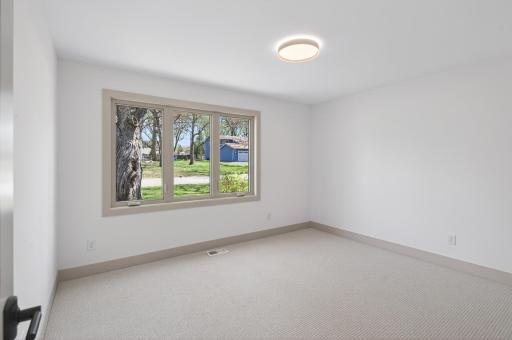 Second main level bedroom features plush carpeting, a neutral palette, and abundant natural light streaming through the large window.