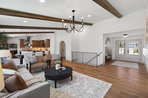 The main level features an open-concept layout filled with natural light, soaring vaulted ceilings, and stunning beams that create a warm yet sophisticated atmosphere.